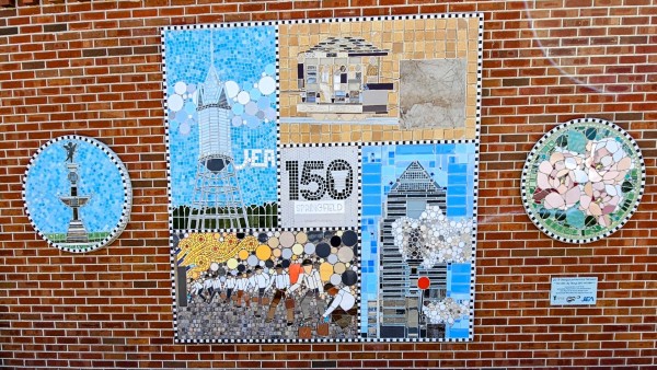 A colorful mosaic mounted on a red brick wall. With several scenes from Jacksonville and Springfield's history surrounding a center piece with "Springfield 150."