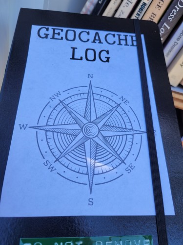 Black notebook with a printed label that says "geocache log"