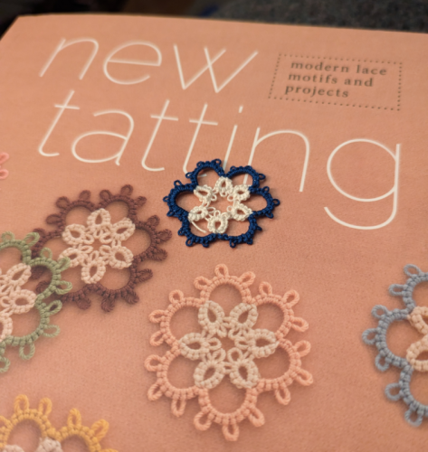 A small blue/white tatted flower motif sits on a copy of the book "New Tatting" by Tomoko Morimoto. The cover of the book has pictures of the same motif done up in different colours. My little tatted piece is a bit more lopsided because of uneven tension, but it's recognizable as being done from the same pattern. 