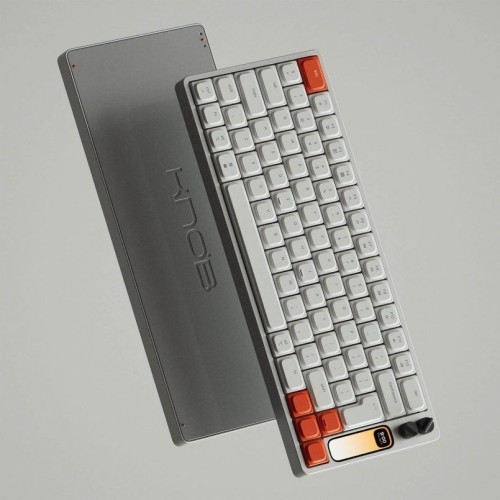 A rendering of a sleek white and orange keyboard with a built-in screen and two multi-function knobs.