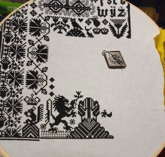 Black and white cross stitch, a lion has appeared, it is standing on its back legs, front paws up in the air. 