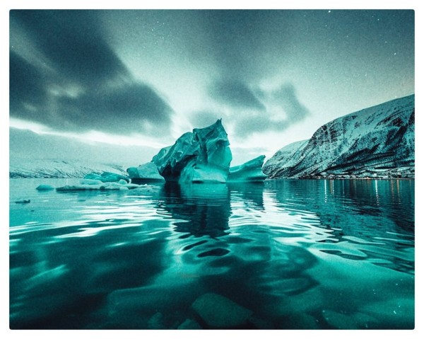 Color photo showing a small iceberg in a small harbor in Norway.
