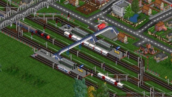 🕶️ A bird's eye view of a station where several suburban or freight trains are approaching or parked, overlooked by a footbridge and a bridge. Near the station a road network and suburban dwellings. The graphics are a bit pixelated considering the age of the game and the close-up.

📚️ Open Transport Tycoon is a libre, multi-platform, single-player / multi-player (up to 255) business simulation game, based and compatible (but autonomous & enhanced) with the Transport Tycoon Deluxe game (1994). The player builds his transport network (trucks, buses, trains, planes & ships) to transport passengers and freight, with the goal of being as profitable as possible. The dividends received by these transports can be reinvested in the extension of the network or the acquisition of vehicles. A mature and actively maintained project.
