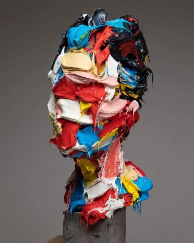 An abstract sculpture of a male bust created using polymer in a range of primary colors.