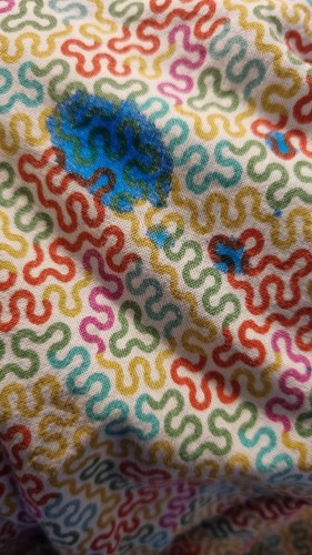 a pice of colourful patterned fabric with big blue blobs of ink on it