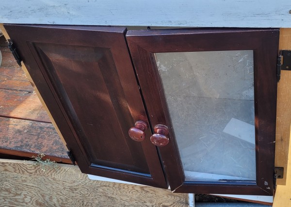 Two cabinet doors on a box. One has wood on it, the other plexiglass.