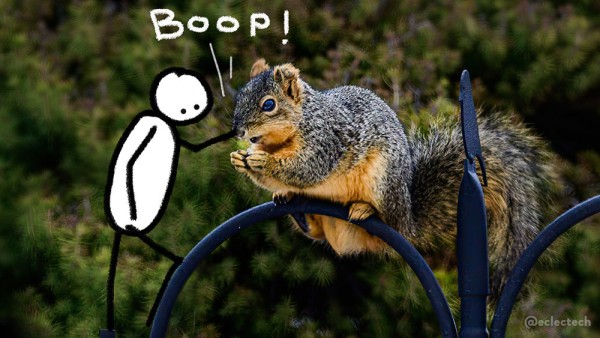 A photo of a squirrel sitting on top of a metal, curved bird feeder, looking left, with a background of dark trees. On its left a simple drawn figure is booping it. The word BOOP! is scribbled above.
