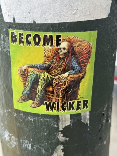 A sticker that says "Become Wicker" in an sort of doom-metal font. In the background is an AI-generated image of a dead body that is sitting in a wooden chair. The body and chair seem to be made out of tree branches and are mingling together.