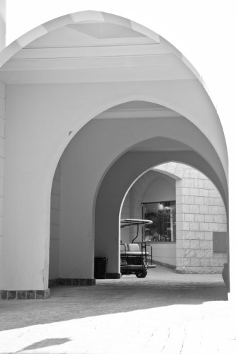 monochrome photo of a hallway in a city leading to a half-hidden golf cart at the end