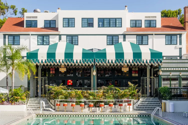 A view of the hotel from the pool.  Chic orange bar stools line the green/white awning covered bar.