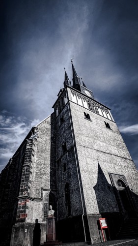 A low-angle view of an imposing old church with a clock tower against a dramatic sky.
Wenzelskirche in Lommatzsch