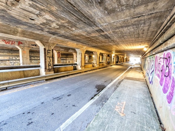 View through the tunneled underpass for Myrtle Avenue beneath the I-95 bridge.  The area is dirty, weathered and nearly covered with graffiti in several places.