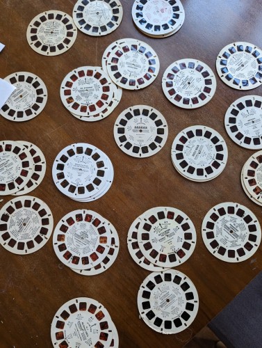 A random assortment of View-Master disks spread across a kitchen table.