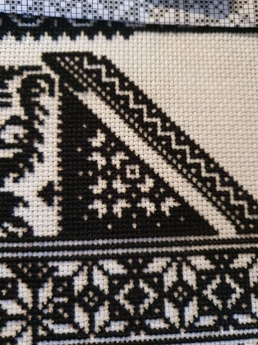 Cross stitch. 
White fabric, black thread. 
A triangle mostly black with some white spaces left to create a pattern.