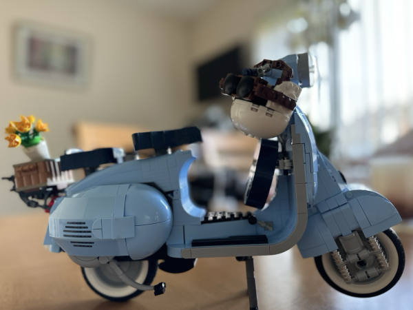 Lego Vespa model. Pale blue with basket of yellow flowers and a white helmet. 
