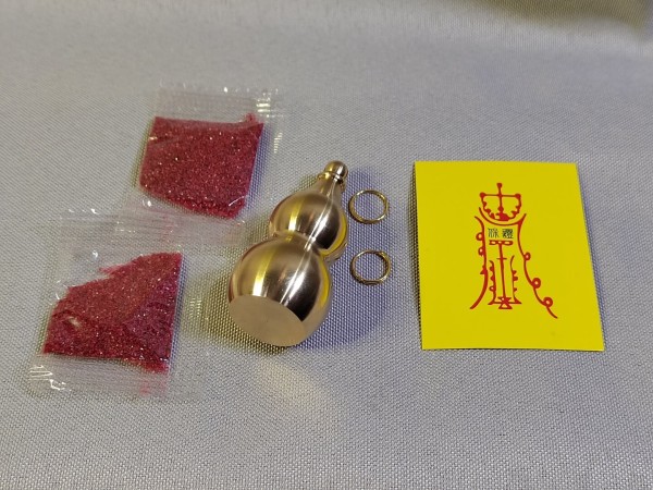 This calabash charm is made of brushed brass again, and comes with a card with the traditional Daoist symbolism over it.  It also comes with two brass-coloured steel rings (for easy attachment to keychains, etc.) and two little satchels of cinnabar powder.

This time I'm not putting the cinnabar into the calabash