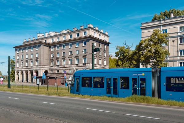A blue tram passing by in front of huge apartment blocks.
