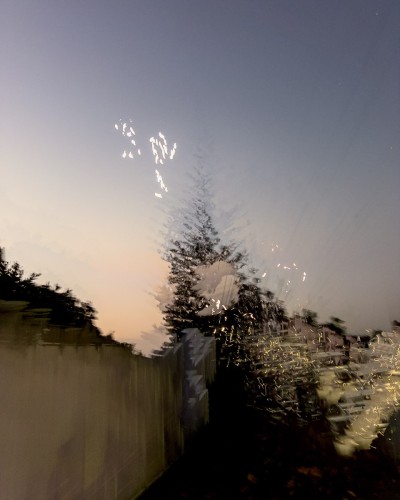This image is an urban landscape photograph of a pine tree silhouetted against a golden twilight sky using glitchy, generative in-camera long exposure to disrupt with fragments, overlays, lights and tracers
