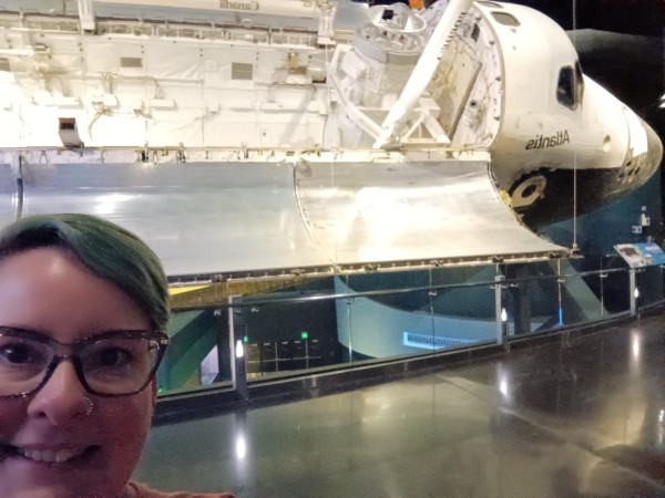 Selfie of me with space shuttle Atlantis in the background, with its body open (as shown at Kennedy Space Center)