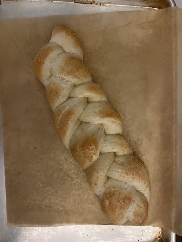 Braided Finnish pulla bread on wax paper on baking pan. 