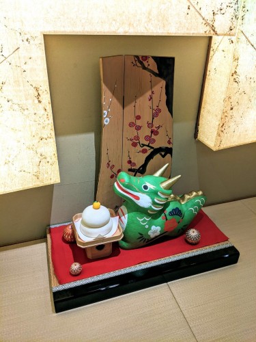 A small green dragon decoration on a small red platform next to a wall