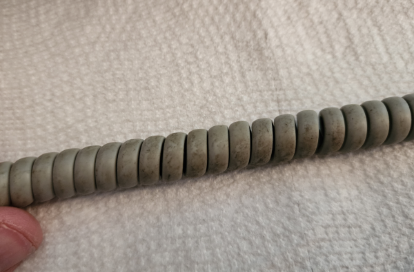 A coiled grey cable. There's dark grime on most of the coils 
