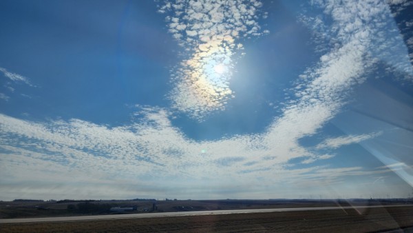 Sunlight refracted over a flat landscape. High altitude clouds and blue sky.