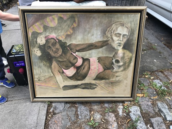 Painting of an old woman lying down wearing a pink bikini. She is holding a severed head and there is another head is beside her. 