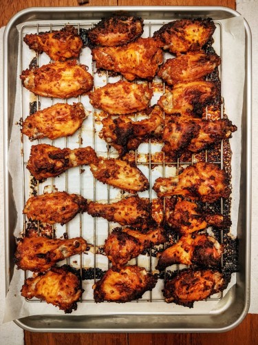 Overhead view of a tray of baked crisp and yellow brown chicken wings