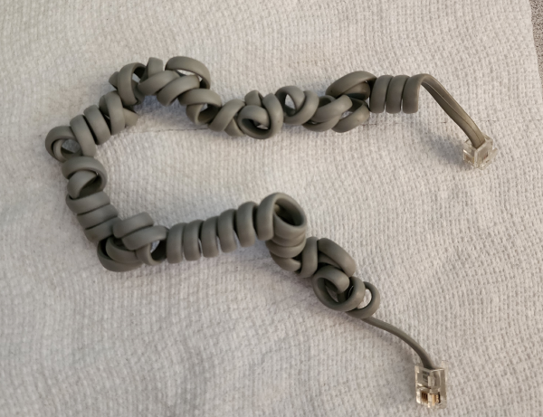 A coiled grey cable. It's grime-free, but it's not longer nicely coiled together, and has a bunch of places where the cable switches chirality 
