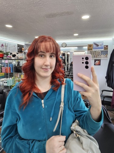 Selfie from the salon with my hair newly dark red and wavy with long bangs