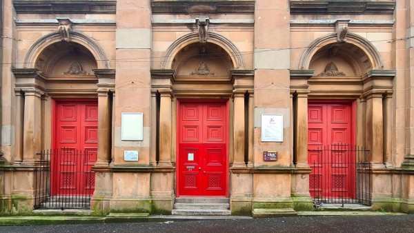 A row of three identical Roman-arched doors on a former Victorian church.