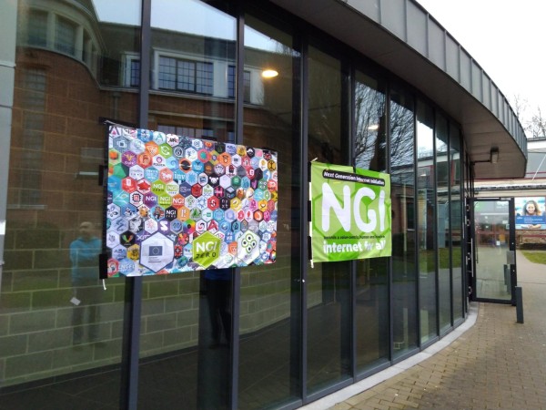 Entrance of Building K with one NGI0 flag and one flag with hexagons of NGI0 projects.