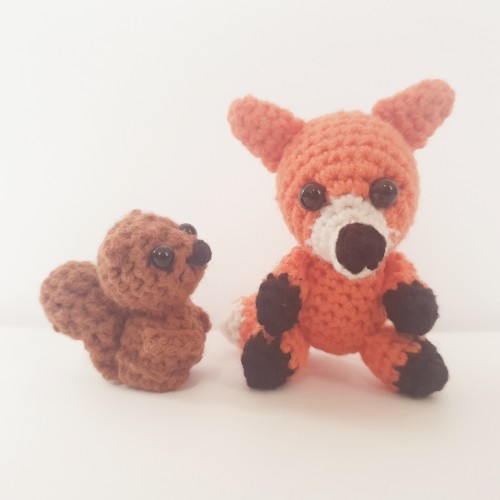 A crocheted amigurumi baby squirrel and a crocheted amigurumi fox