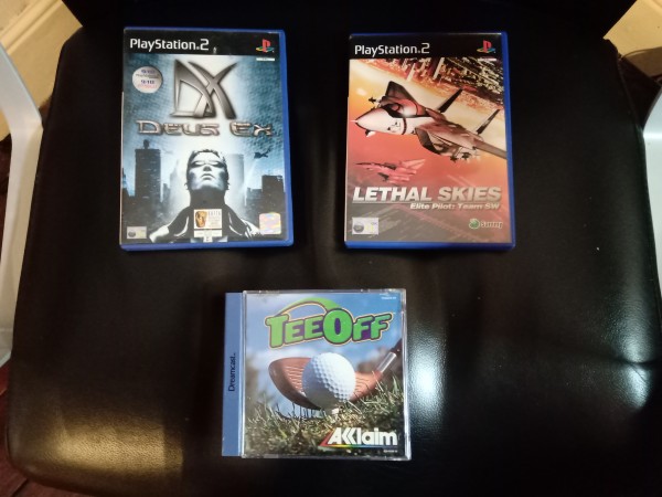 Boxed video games: "Deus Ex" and "Lethal Skies" for PS2, and "Tee Off" for Dreamcast.