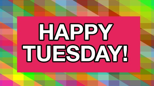 The image has a vibrant background with a mosaic of different colors arranged in diamond shapes. The colors include shades of green, blue, red, yellow, and more, creating a kaleidoscopic effect. In the center, there is a bold, pink rectangle with the words "HAPPY TUESDAY!" written in large, white block letters. The overall feel of the image is cheerful and bright.