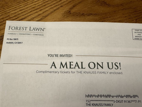 A photo of a postal mailer from Forest Lawn (“Funerals • Cremations • Cemeteries”) offering “A MEAL ON US!”