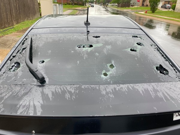 the rear window of a Toyota Prius with multiple large holes from hailstones
