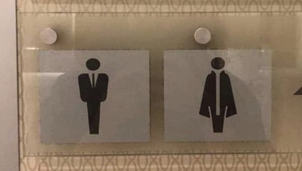 Washroom signs that are graphic representations of people. The first is a person in a dark suit and tie. The second is a person in an opera cape and feather boa