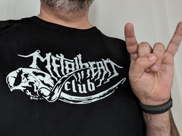 selfie wearing my brand new metalhead.club T-Shirt and making the traditional metal greeting sign of the horns (no face, just parts of a gray beard can be seen)