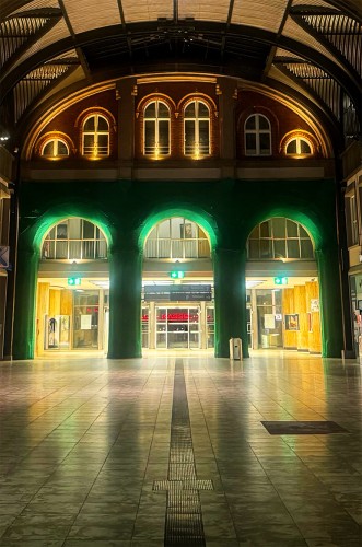Die Wartehalle vom Kasseler Hauptbahnhof - abends fotografiert. 
In der Mitte sind die Torbögen in einem dunklen Grünton, weil diese von einem grünen Netz verhüllt sind, da sie scheinbar restauriert werden. Oben an der Decke sind die Fenster-Bögen im rotbraunen Backstein zu sehen. Der Hintergrund zum Eingang hin scheint in einem goldgelben Ton.