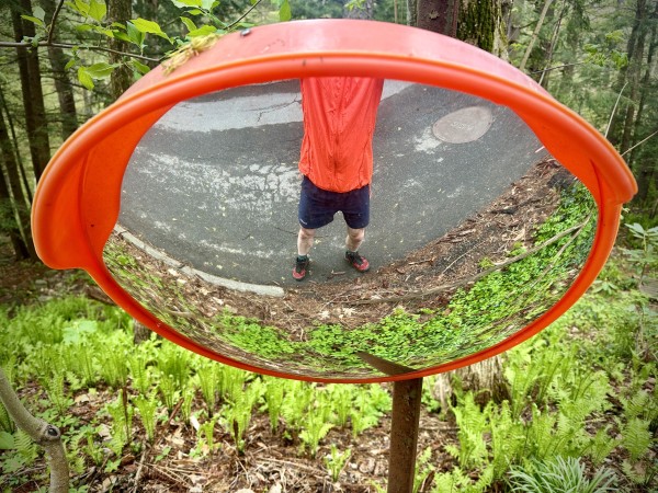 Shortcut between trails had this mirror across from house’s driveway so I took a selfie!  “:^)
Mirror is a bright orange plastic which matches my windbreaker, there’s a big patch of bright green ferns on forest floor behind mirror