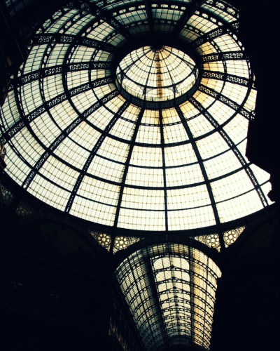 Light coming through the glass dome and roof of the shopping gallery in Milan. The other parts of the building are dark.